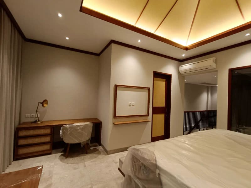 Area meja kerja di dalam kamar villa dengan meja kayu dan lampu baca