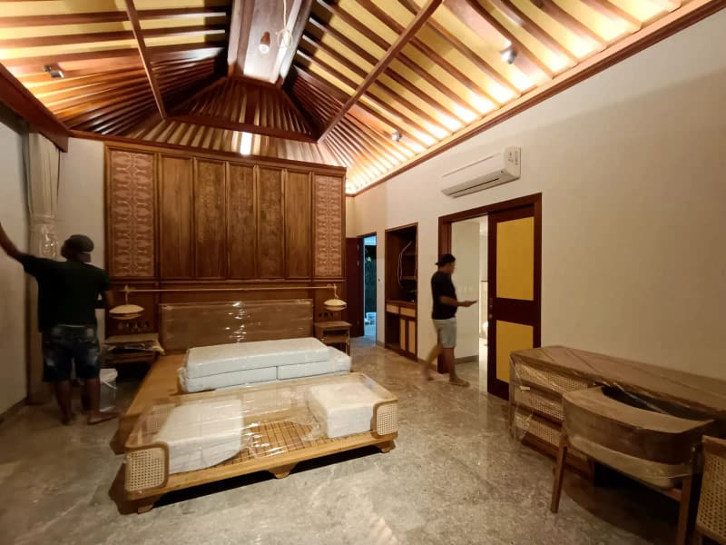 Dua pekerja memasang interior kamar villa dengan plafon kayu bergaya joglo