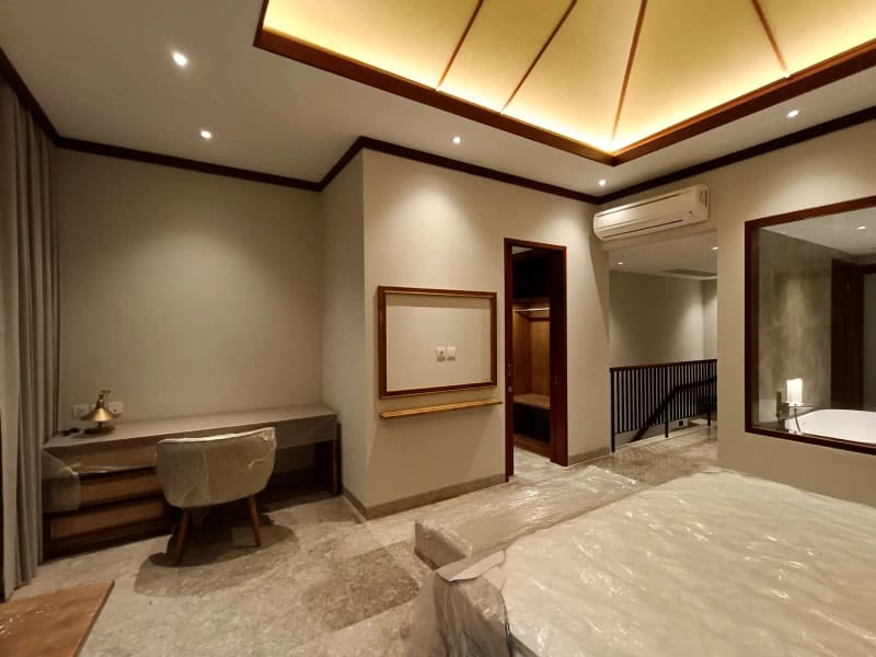 Kamar tamu villa dengan cermin dinding, meja kayu, dan pencahayaan hangat